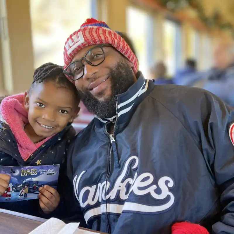 Father and Daughter holding the North Pole Express ticket during the Christmas train ride