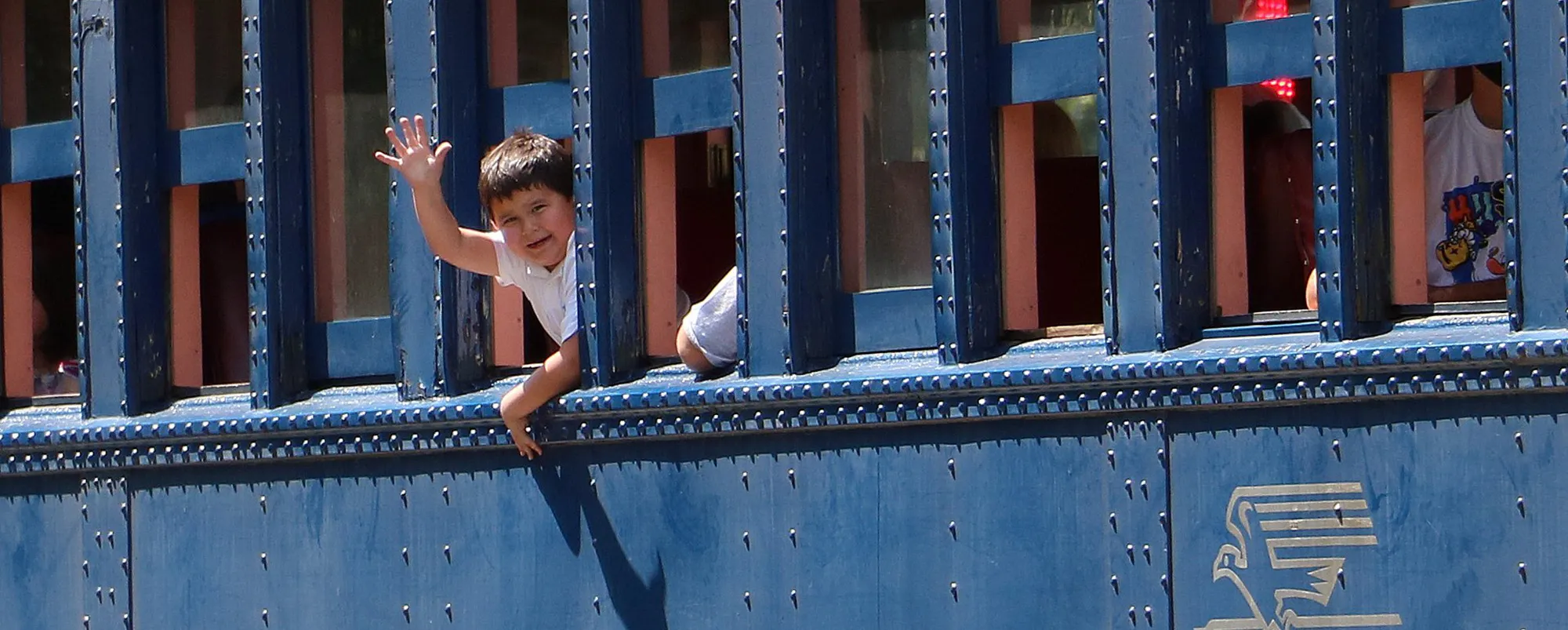 118988514_1274823042909891_5274399619723939889_o a young boy waving from inside of a train car during a educational group field trip