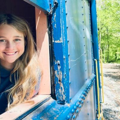 Young girl looking out her train car window smiling