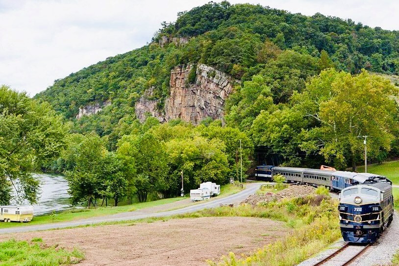 camper-train a train traveling down train tracks near a forest